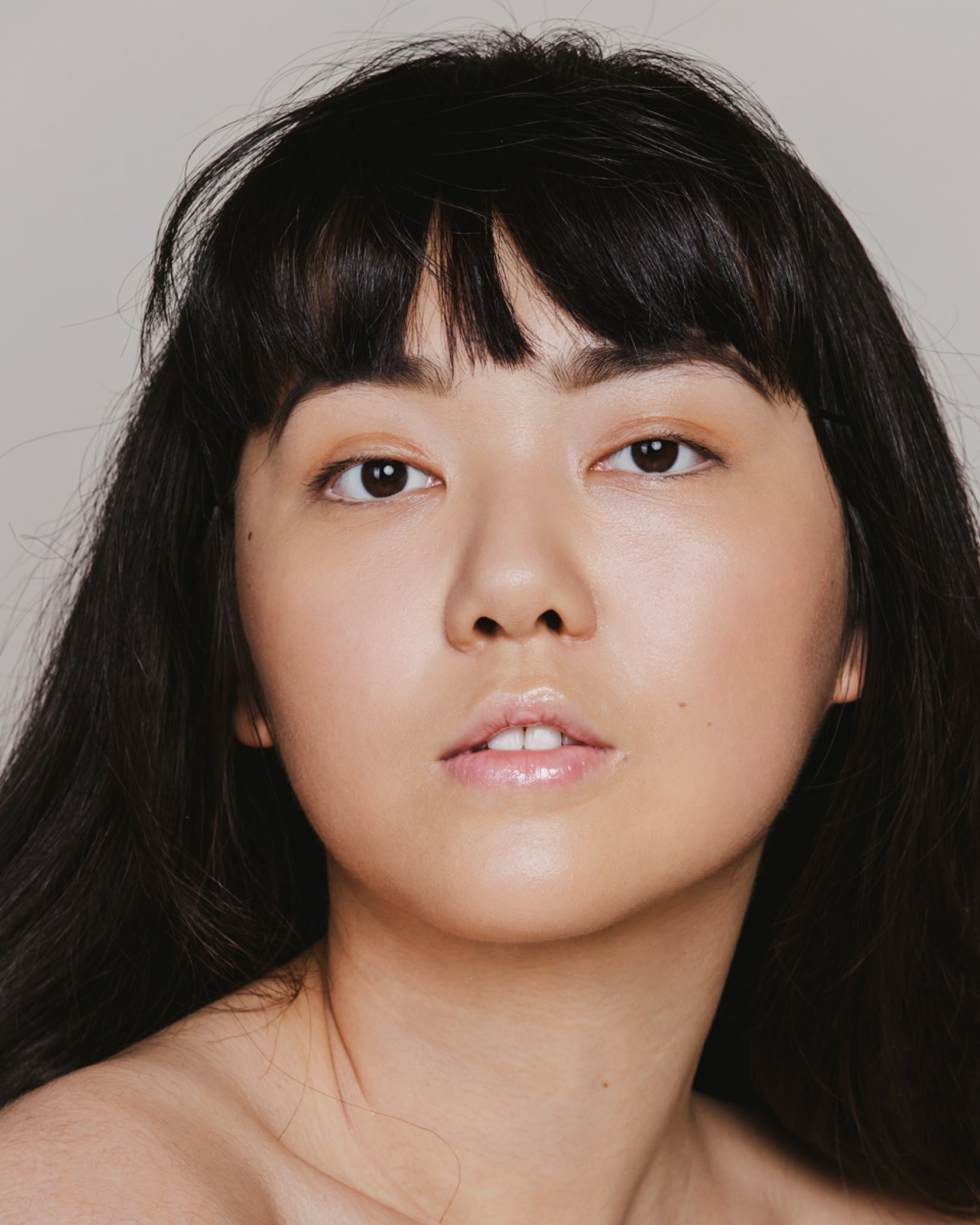 Model wearing MÁDARA Organic Skincare skin equal sand on A6057 on skin; close-up portrait shows natural application results.