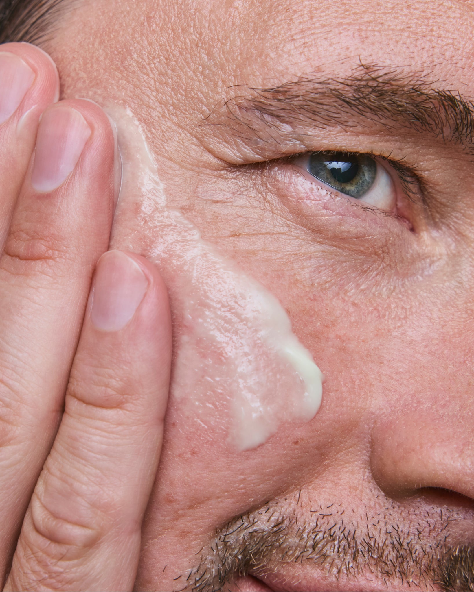 Model wearing MÁDARA Organic Skincare vitamin c face cream for men A5003 face cream on skin; close-up portrait shows natural application results.